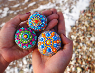 persons hands holding painted rocks